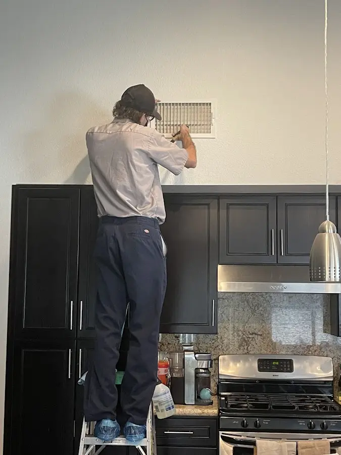 Technician inspecting an air vent during HVAC service in Northdale
